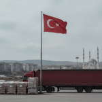 İstanbul'da bir fabrika yükleme alanı: Türk bayrağı, kırmızı dorse ve uzakta cami minareleri